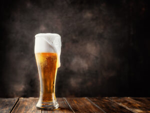 Glass of fresh and cold beer on dark background