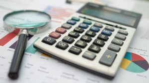 Magnifying Glass  And Calculator On Charts Graphs Paper. Financi