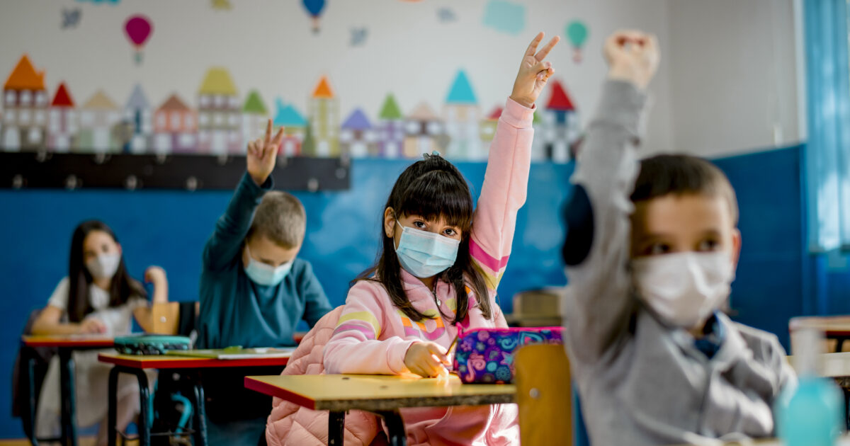 Elementary schoolchildren wearing a protective face masks  in the classroom. Education during epidemic.